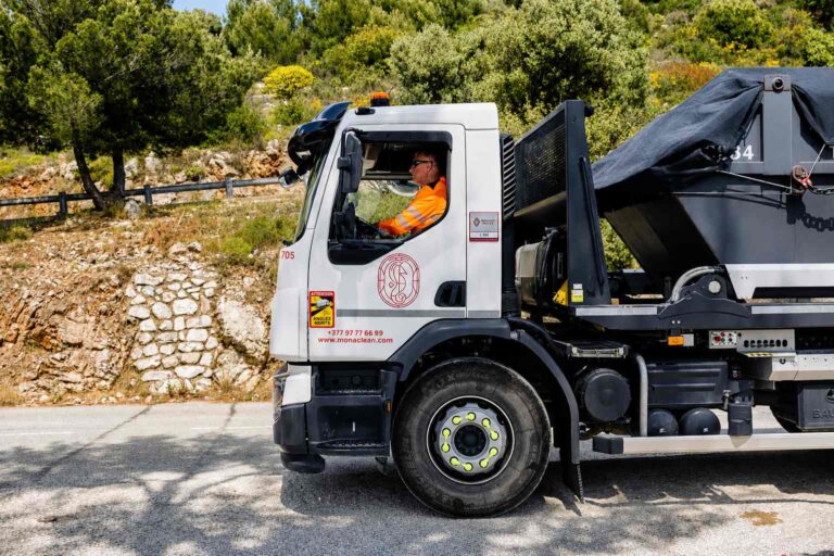 Camion-benne Monaclean en intervention à Monaco et sur la Côte d’Azur, conduit par un agent en tenue haute visibilité.